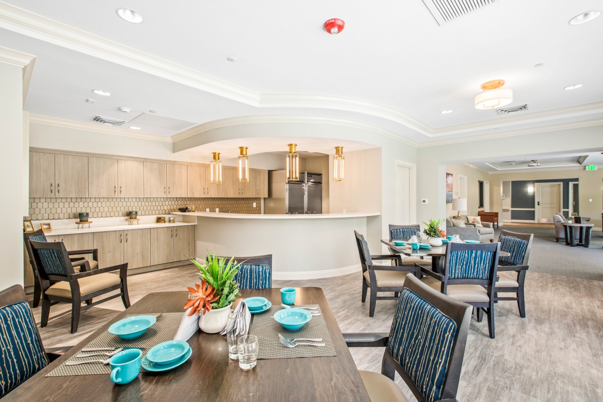 A modern dining area with an open kitchen, featuring stylish furniture and decor.