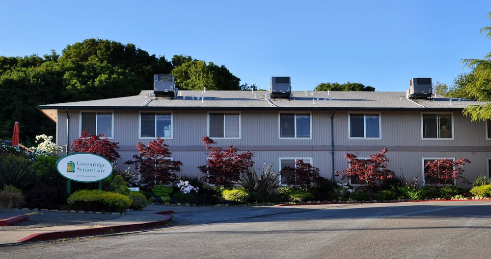 A residential building with landscaped front garden and trees, captured on a clear day.