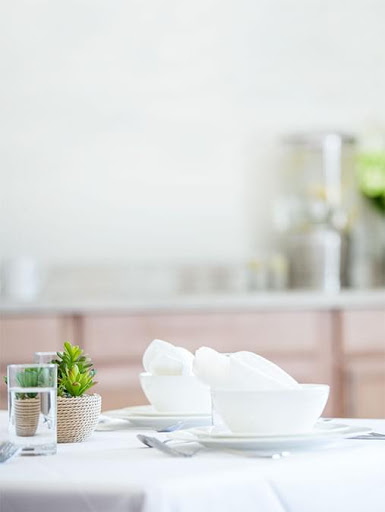 A beautifully arranged dining table featuring minimalist white dinnerware and a touch of greenery.