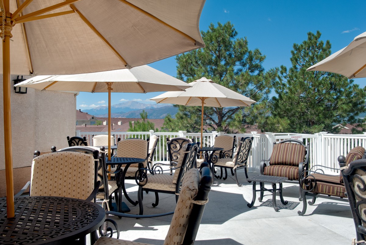 A sunny outdoor patio with tables, chairs, and umbrellas, offering a relaxing atmosphere.