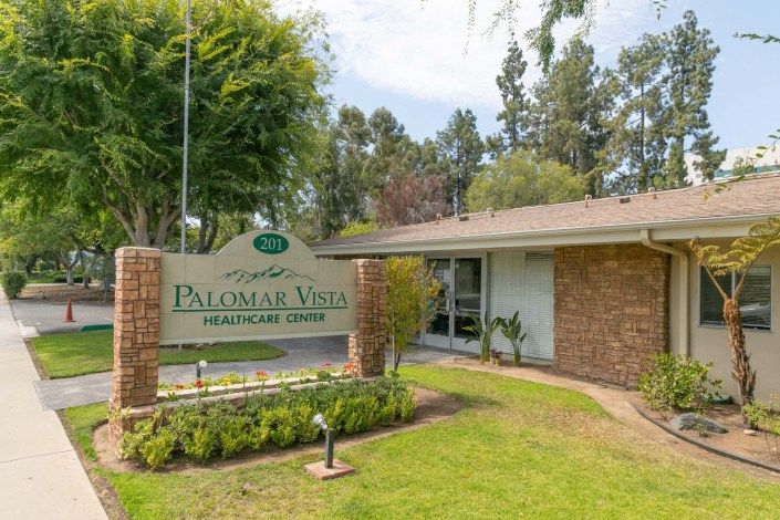 A view of a building entrance with a prominent sign and well-maintained landscaping.