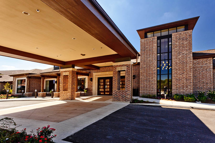A modern brick building entrance with a large canopy and driveway.