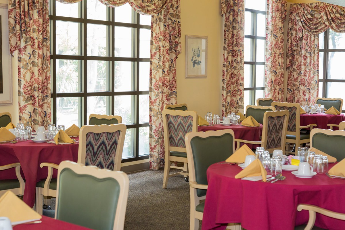 A cozy dining room with elegantly set tables and large windows.