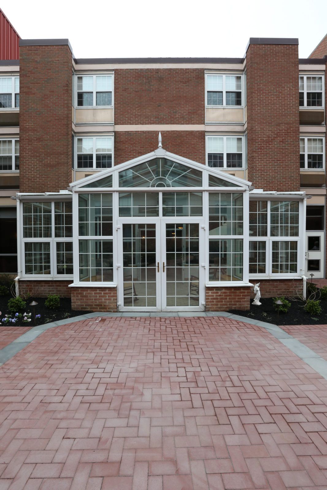 The image shows the glass entrance of a brick building with multiple windows.