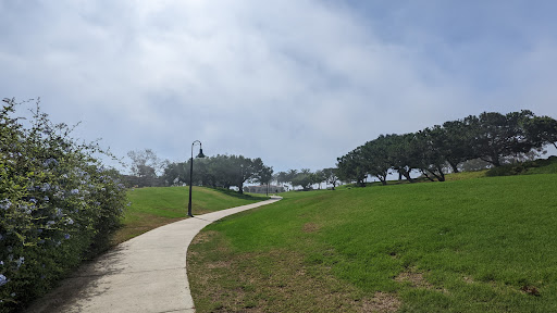 A winding pathway through a lush green park under a cloudy sky.