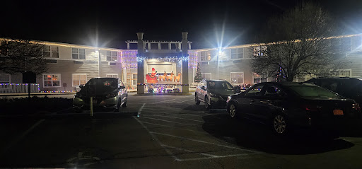 A brightly lit hotel entrance at night, surrounded by parked cars.
