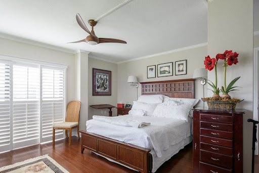 A cozy and elegantly designed bedroom featuring a wooden bed, stylish ceiling fan, and tasteful decor.