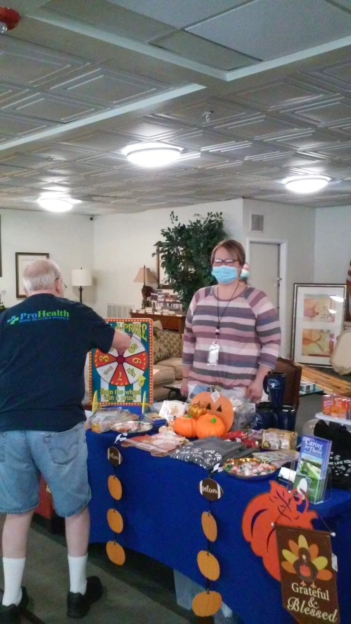 Two people interacting at a craft fair stall with various items on display.