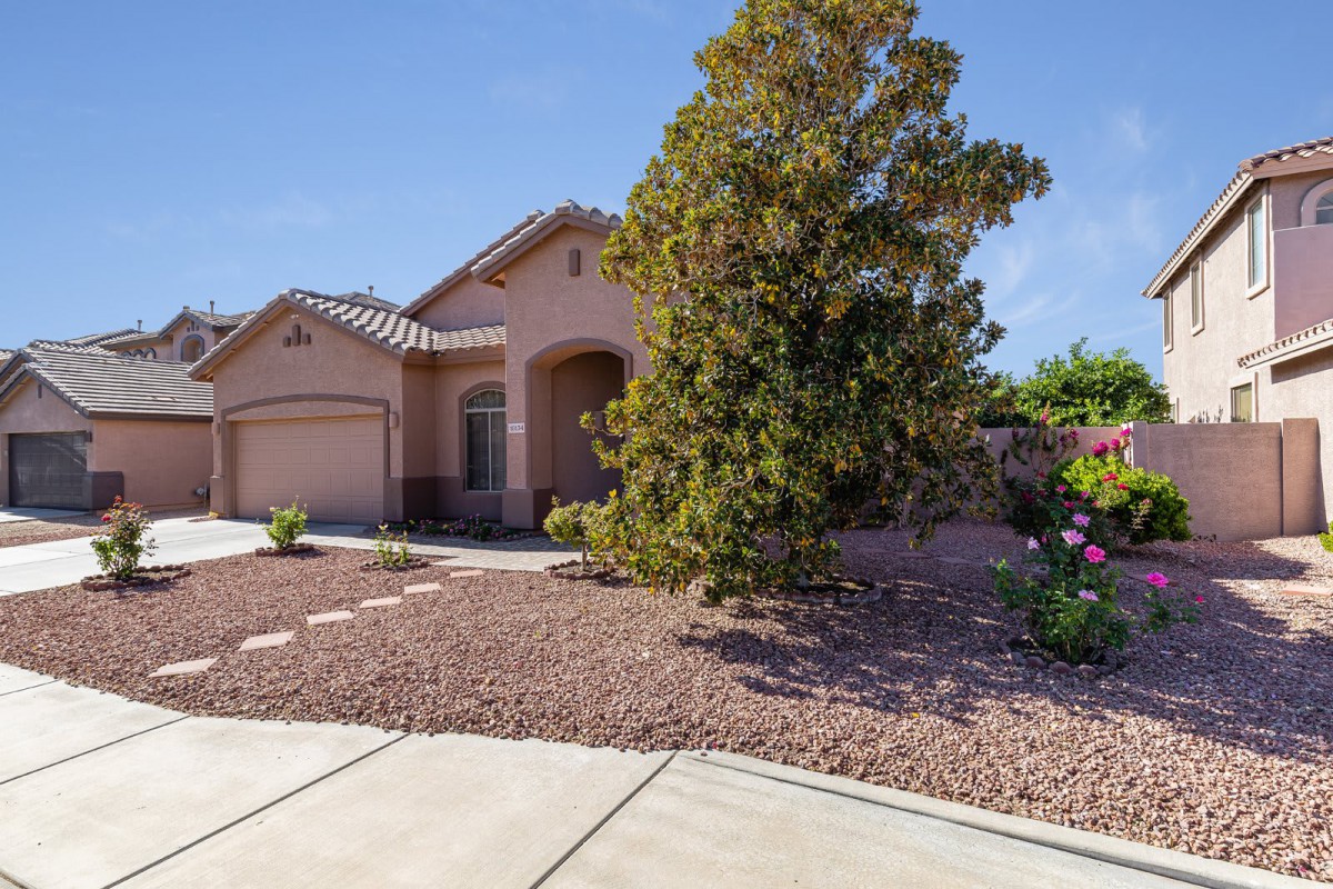 A suburban house with landscaped front yard and driveway under a clear blue sky.