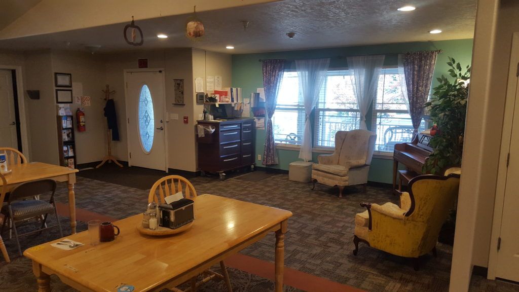 Cozy living room with a dining table and chairs, featuring large windows and comfortable seating.