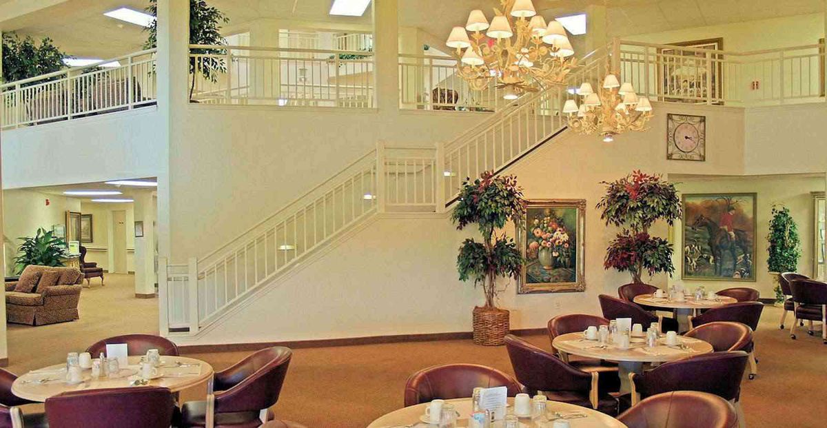 A spacious dining area with elegant chandeliers and a grand staircase.