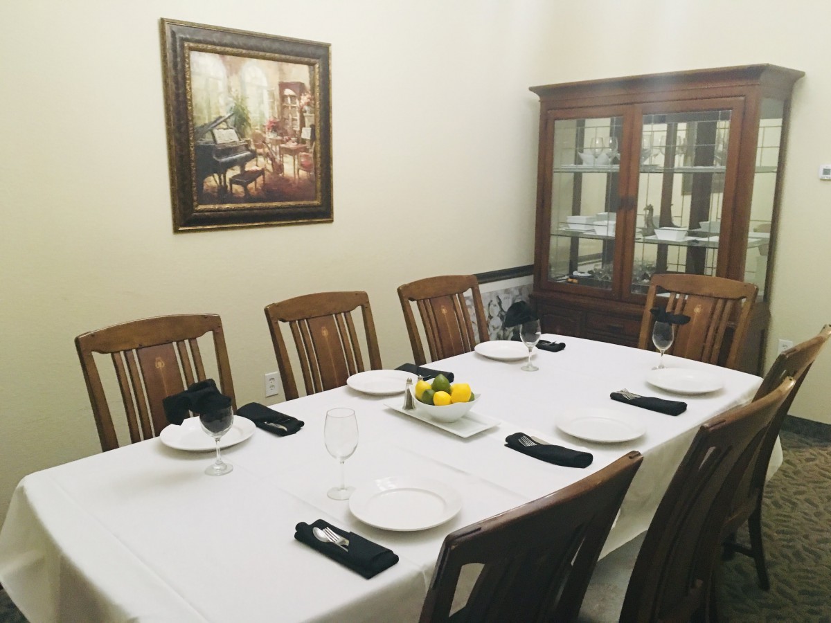 A formal dining room setup with a white tablecloth, neatly arranged plates, and black napkins.