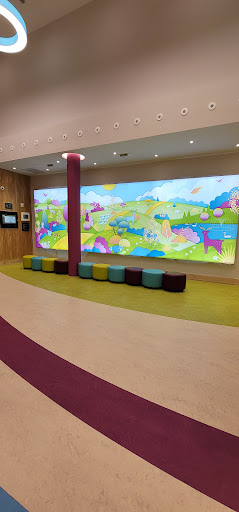 A vibrant and playful waiting area designed for children, featuring a large colorful mural and cozy seating.