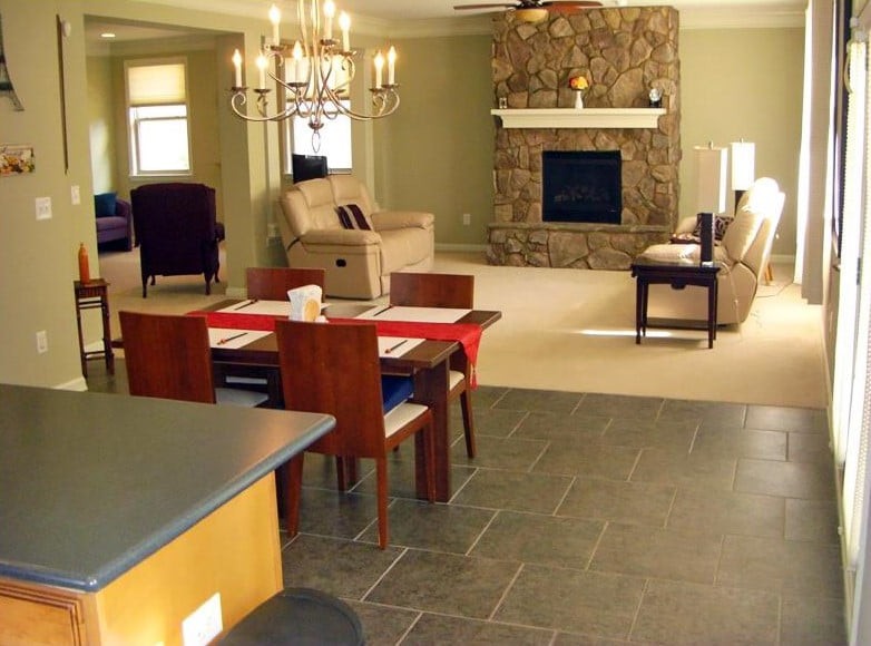 An open-concept living and dining area featuring a stone fireplace, a chandelier, and modern furniture.