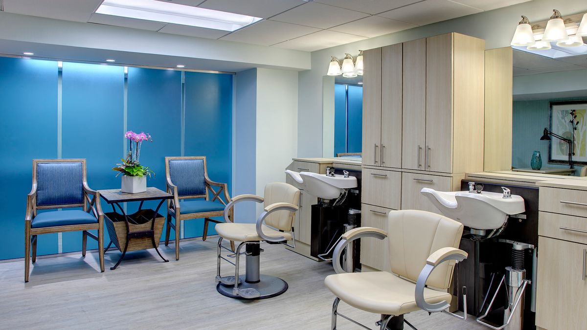 A modern salon interior with stylish chairs and hair washing stations against a backdrop of blue walls.