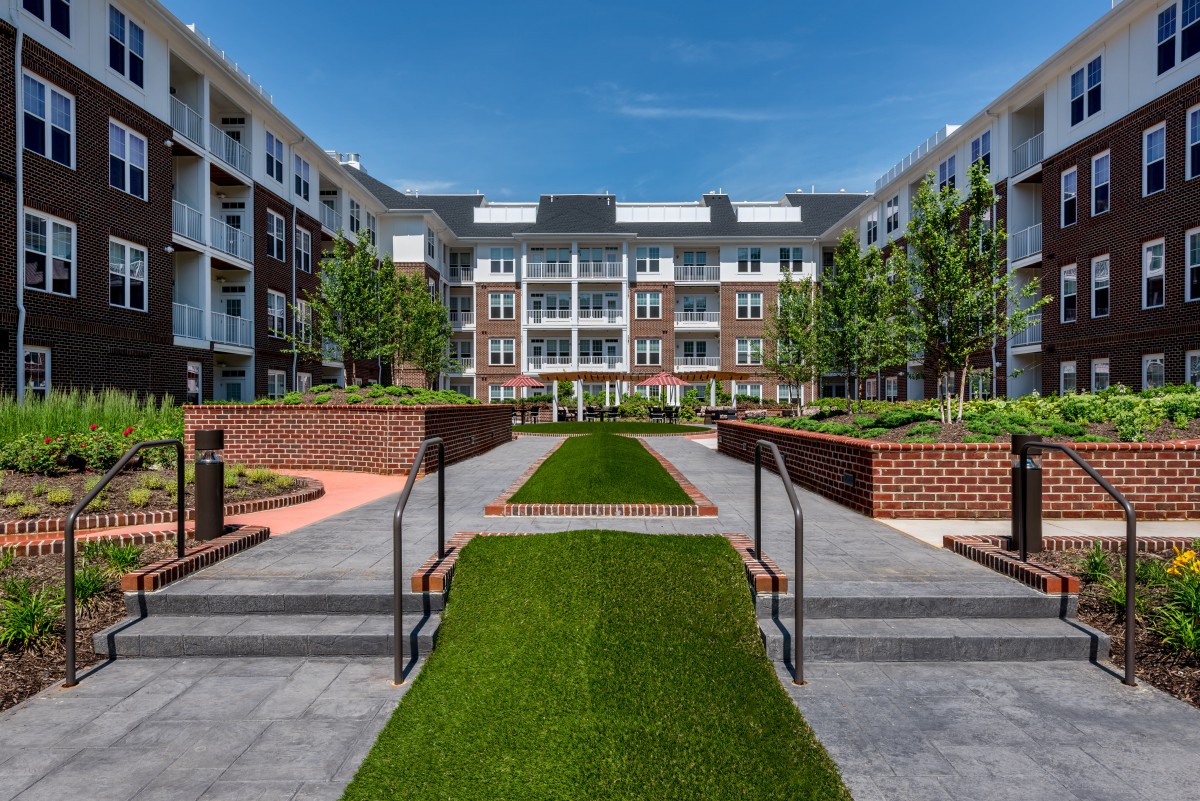 A modern apartment complex featuring a landscaped courtyard with pathways and green spaces.