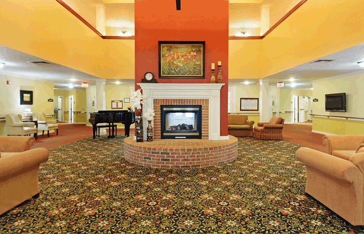 A spacious hotel lobby featuring a central fireplace, a grand piano, and comfortable seating areas.