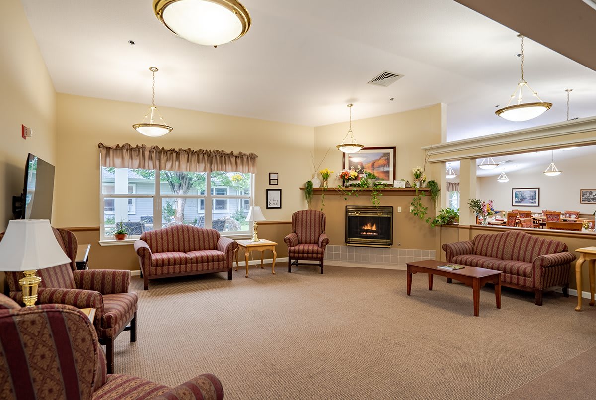 A cozy living room with sofas and a fireplace, featuring warm lighting and elegant decor.