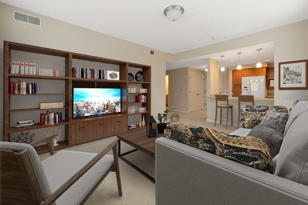 A modern living room with comfortable seating, a large TV, and an open view into the kitchen area.