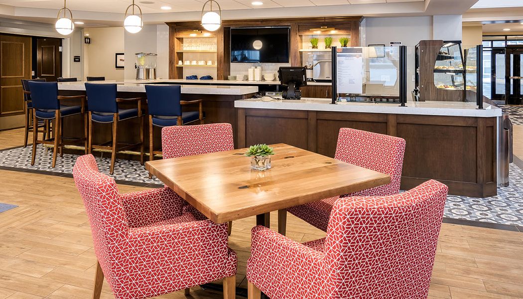 A modern dining area with a wooden table and patterned red chairs.