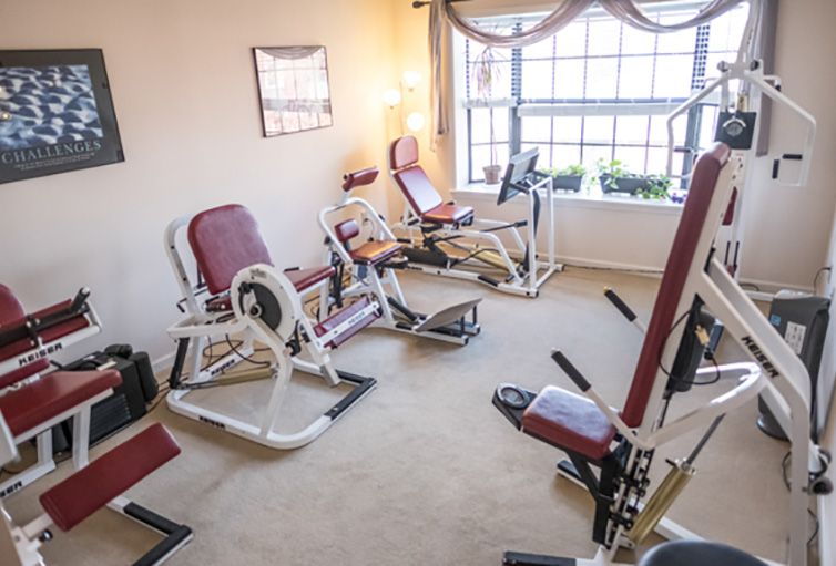 A cozy home gym with various exercise equipment and natural lighting.