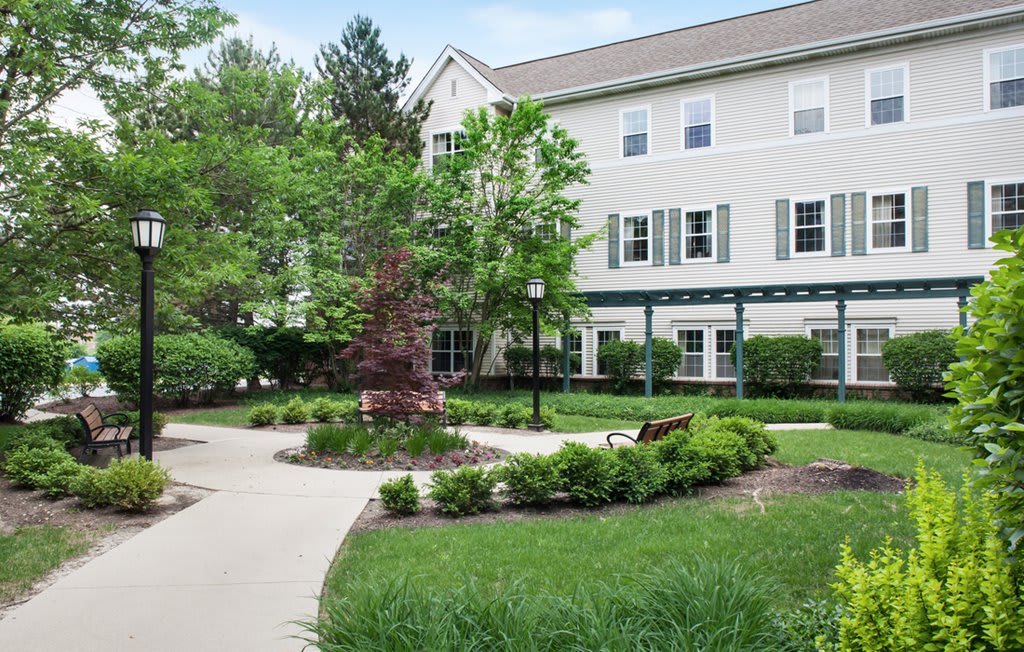 A well-maintained courtyard with greenery, benches, and a multi-story building in the background.