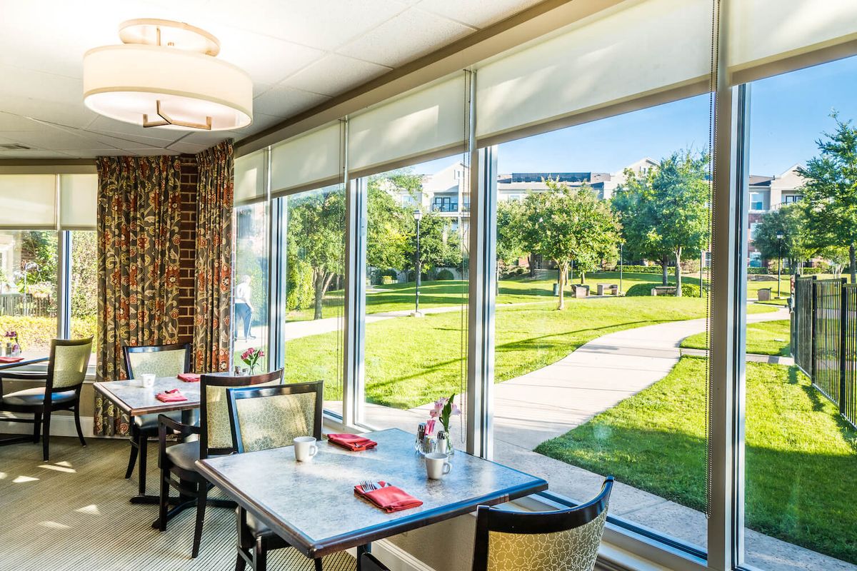 A cozy restaurant interior with a scenic view of a lush, green outdoor area through large windows.