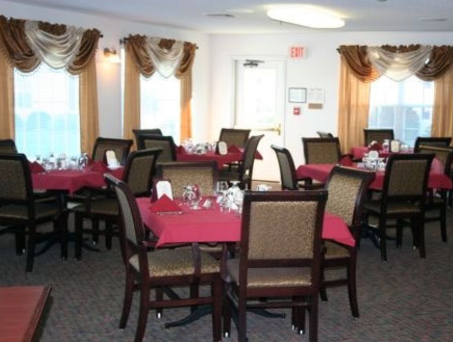 A dining room with tables set with red tablecloths and neatly arranged chairs.