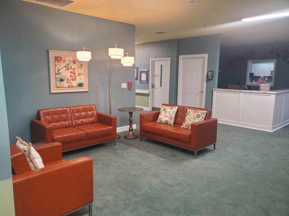 A cozy living room with orange sofas, a standing lamp, and artwork on the wall.