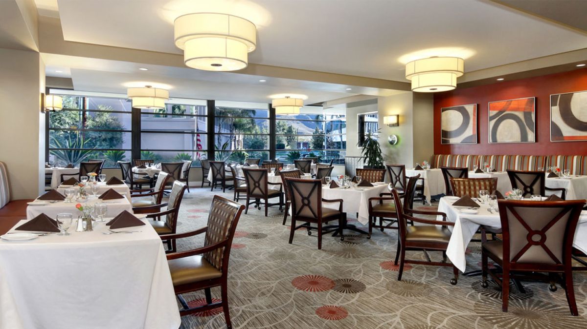 An elegant dining area with neatly arranged tables and chairs, featuring warm lighting and tasteful decor.