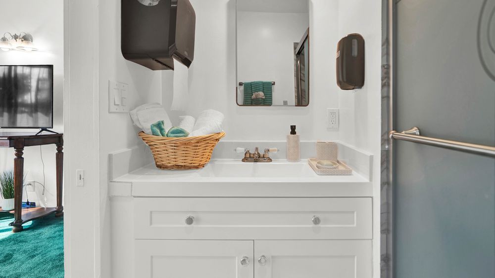 A clean and organized bathroom sink area with a basket of towels and a soap dispenser.