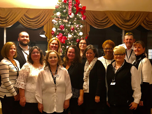 A joyful gathering of team members celebrating the festive season in front of a beautifully decorated Christmas tree.