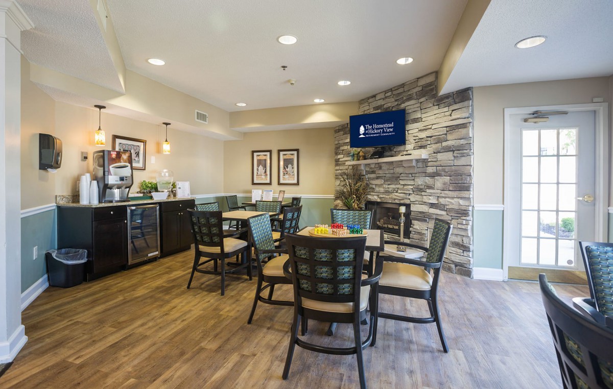 A cozy dining area with tables and chairs, featuring a television mounted on a stone wall.