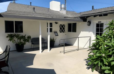 A quiet backyard with a patio, featuring a ramp and outdoor seating.
