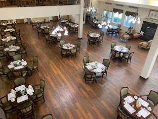 A spacious dining room with elegantly set tables and chairs on a wooden floor.