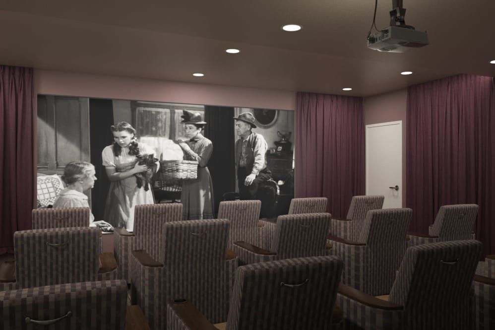 A cozy home theater room with vintage decor and retro seating, featuring a large black-and-white movie projection.