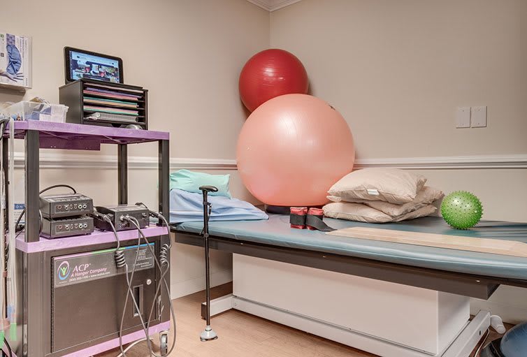 A physical therapy room with exercise balls and medical equipment.