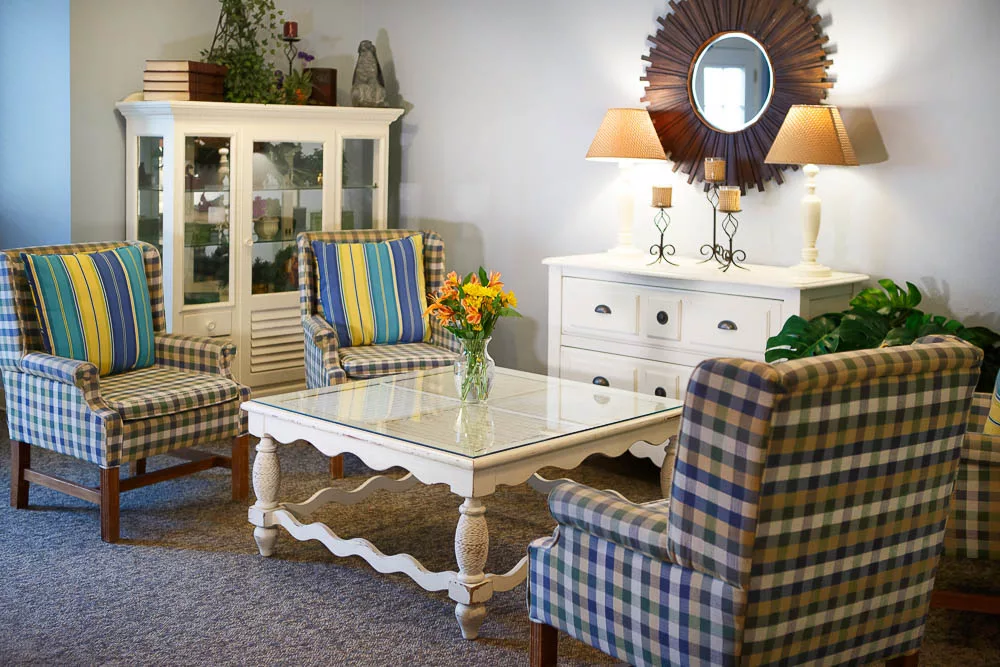 A cozy living room featuring a white coffee table, patterned armchairs, and elegant decor with warm lighting.