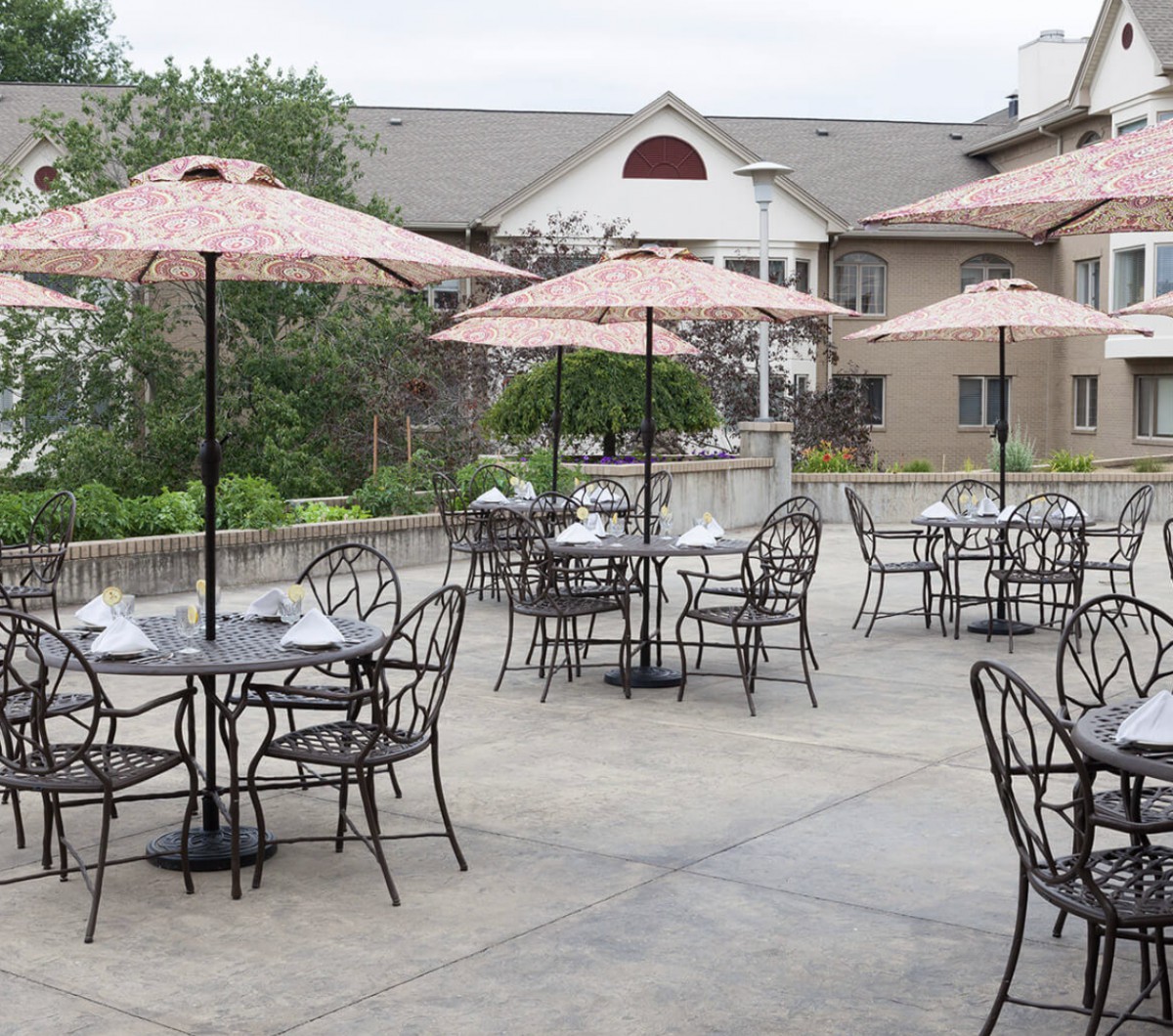 Outdoor patio area with tables and umbrellas in a garden setting.