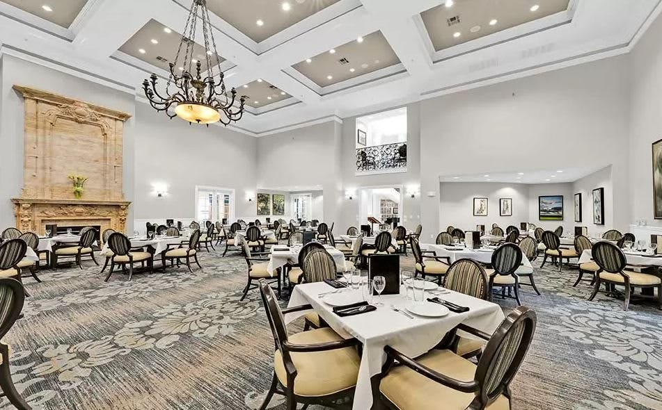 An elegant dining room with chandeliers and neatly set tables.