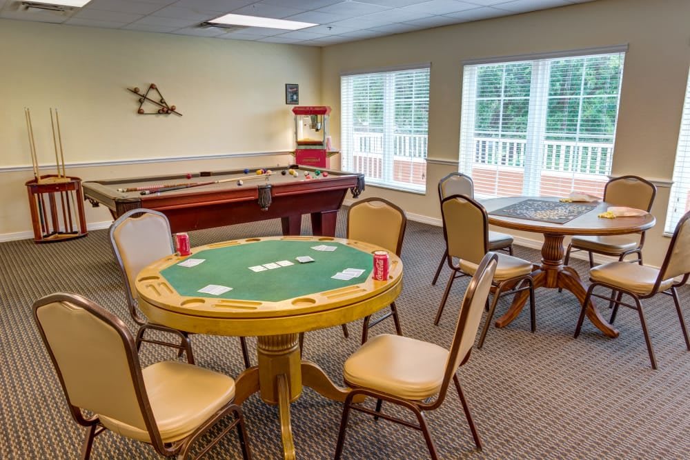 A cozy game room featuring a poker table, shuffleboard, and comfortable seating.