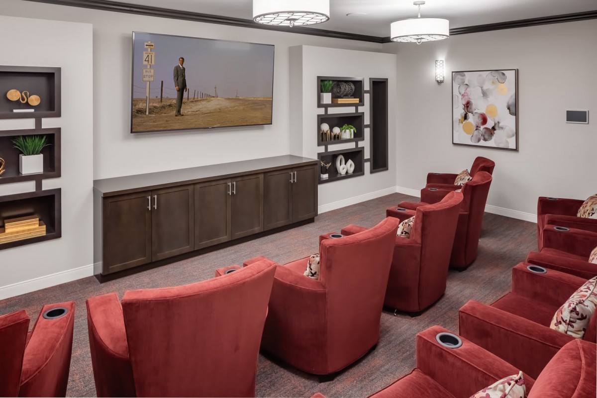 A cozy home theater setup with red chairs and a large screen.