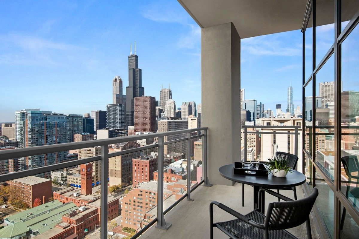 A stunning cityscape view from a modern balcony featuring outdoor seating.