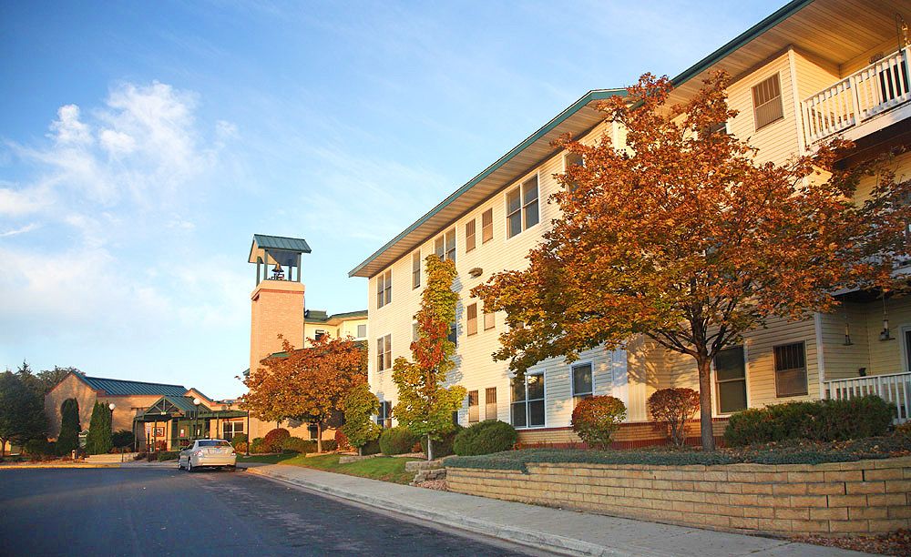 A college building with a clock tower surrounded by autumn foliage.