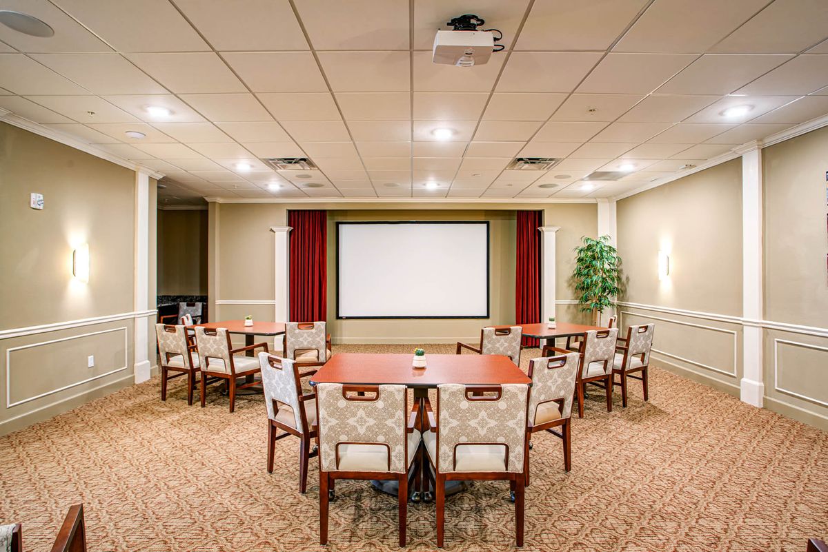 A well-organized conference room featuring a central projector and seating arranged around tables.