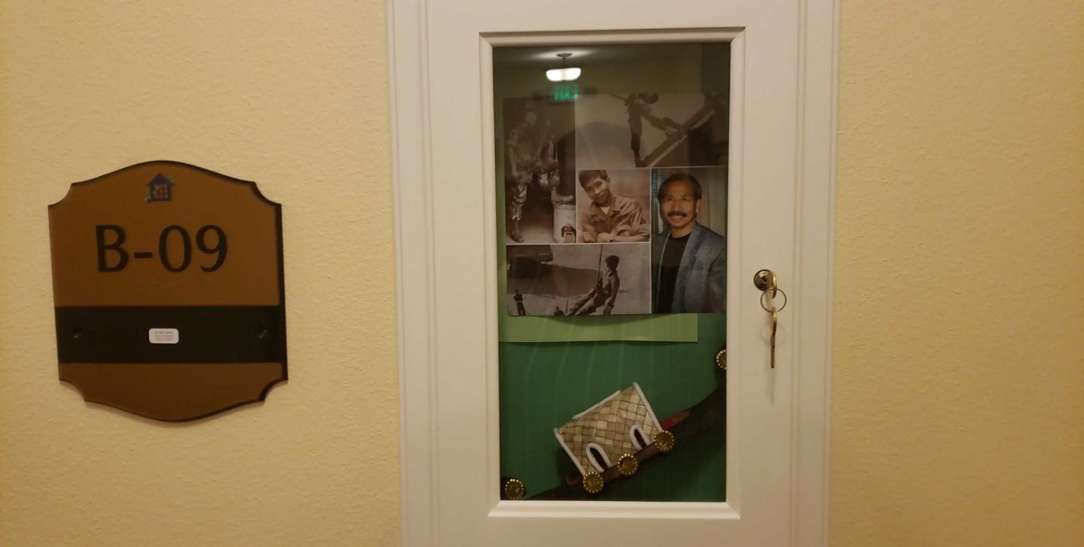 A door with a glass window featuring various posters and a distorted keyhole.