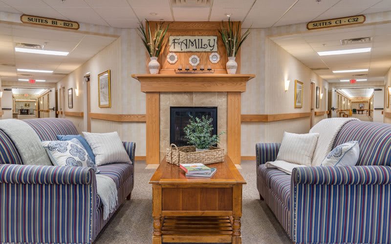 A cozy living room featuring a central fireplace, surrounded by comfortable sofas and homely decor.