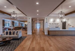 A modern hotel lobby with a reception desk, wooden flooring, and stylish lighting.