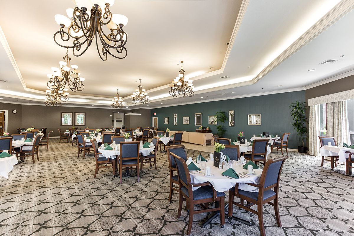 A spacious and elegantly designed dining room with chandelier lighting and meticulously arranged tables, creating a sophisticated atmosphere.