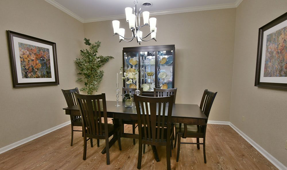 A well-furnished dining room with a dark wood dining set and a chandelier.